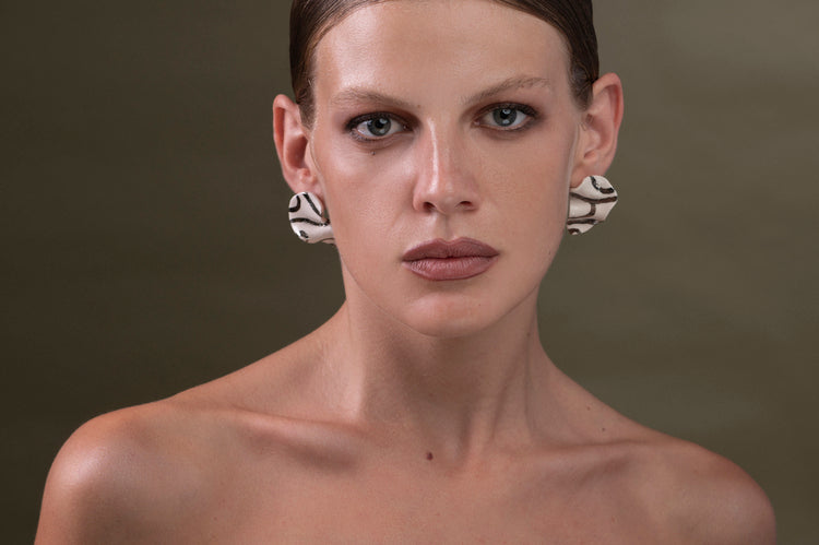 Orecchini Corrente in ceramica, linee sinuose, intrecci di oro e argento, design raffinato e moderno, piccoli e luminosi.